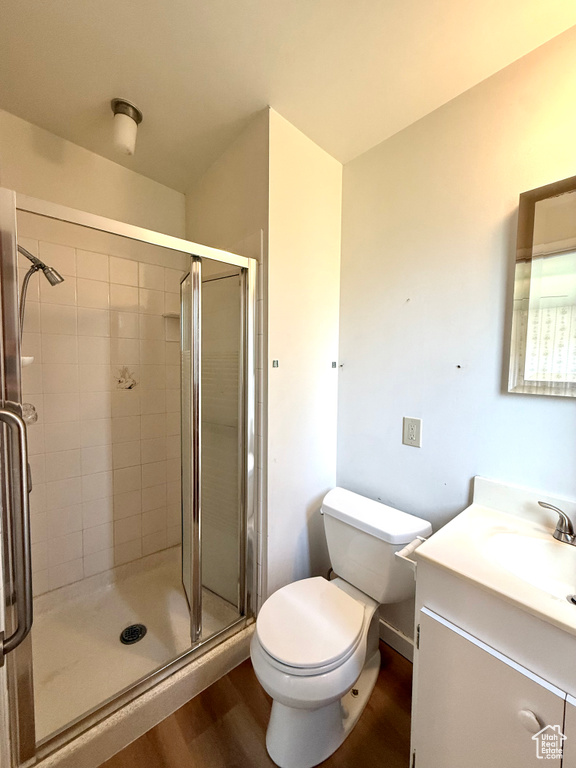 Full bath with vanity, toilet, wood finished floors, and a stall shower