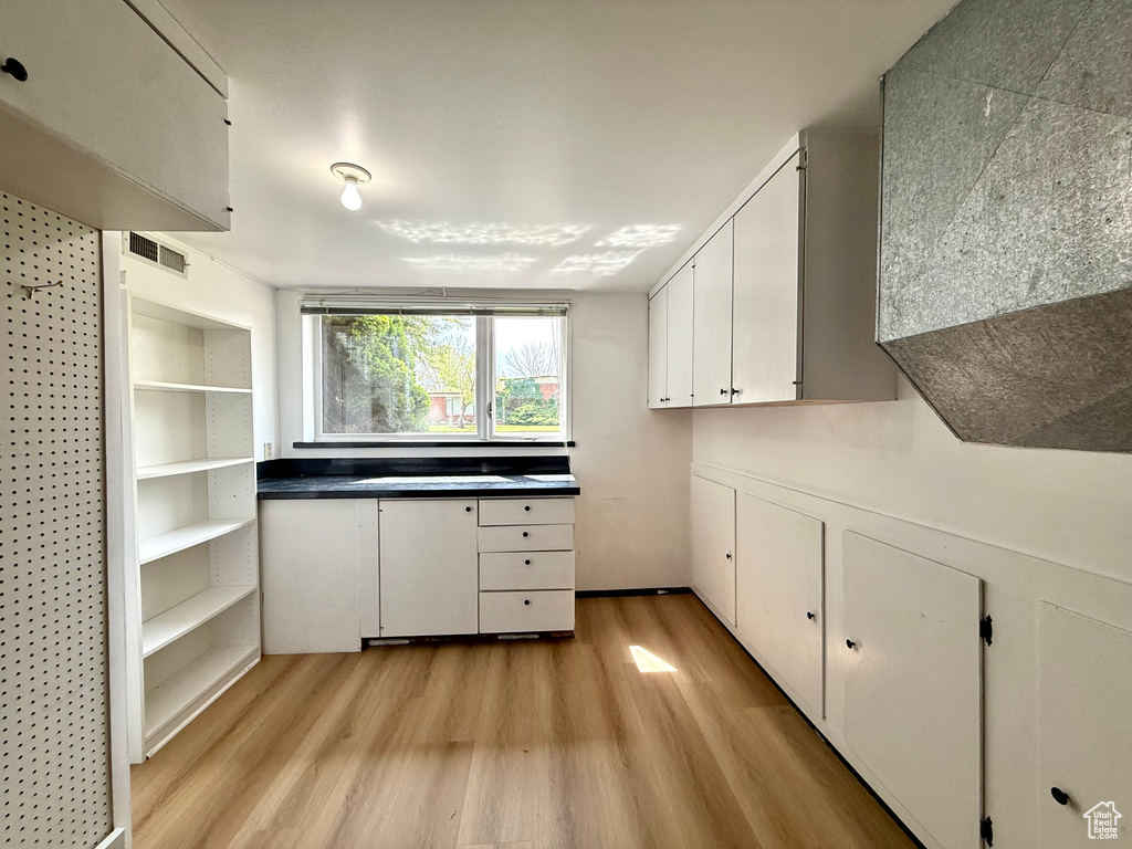 Kitchen with white cabinetry, visible vents, and light wood finished floors