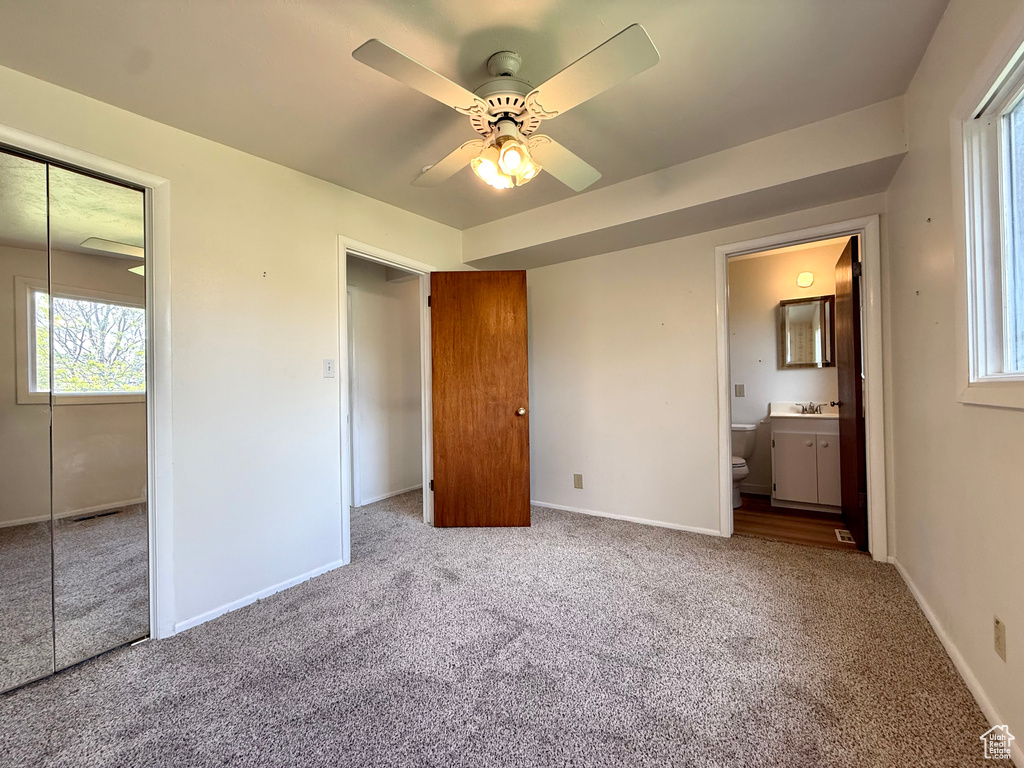 Unfurnished bedroom featuring a closet, multiple windows, and carpet flooring