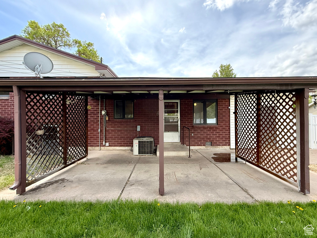 Rear view of house featuring brick siding, a patio area, and central AC