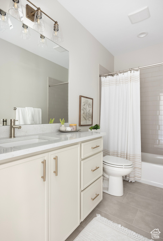 Bathroom with vanity, tile patterned flooring, shower / bath combination with curtain, and toilet