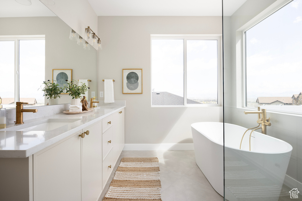 Full bathroom featuring baseboards, a freestanding tub, a sink, and tile patterned floors