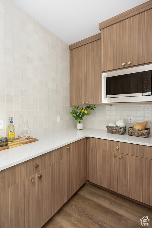 Kitchen with light countertops, decorative backsplash, and built in microwave