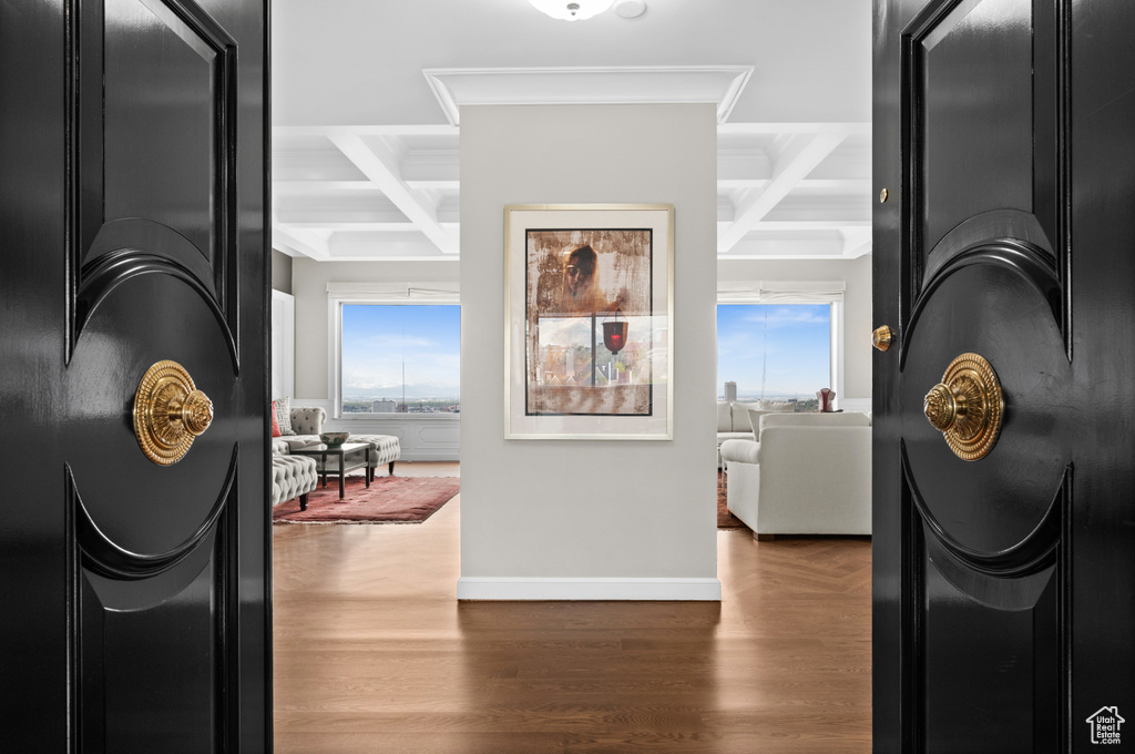 Corridor featuring crown molding, beam ceiling, wood finished floors, baseboards, and coffered ceiling