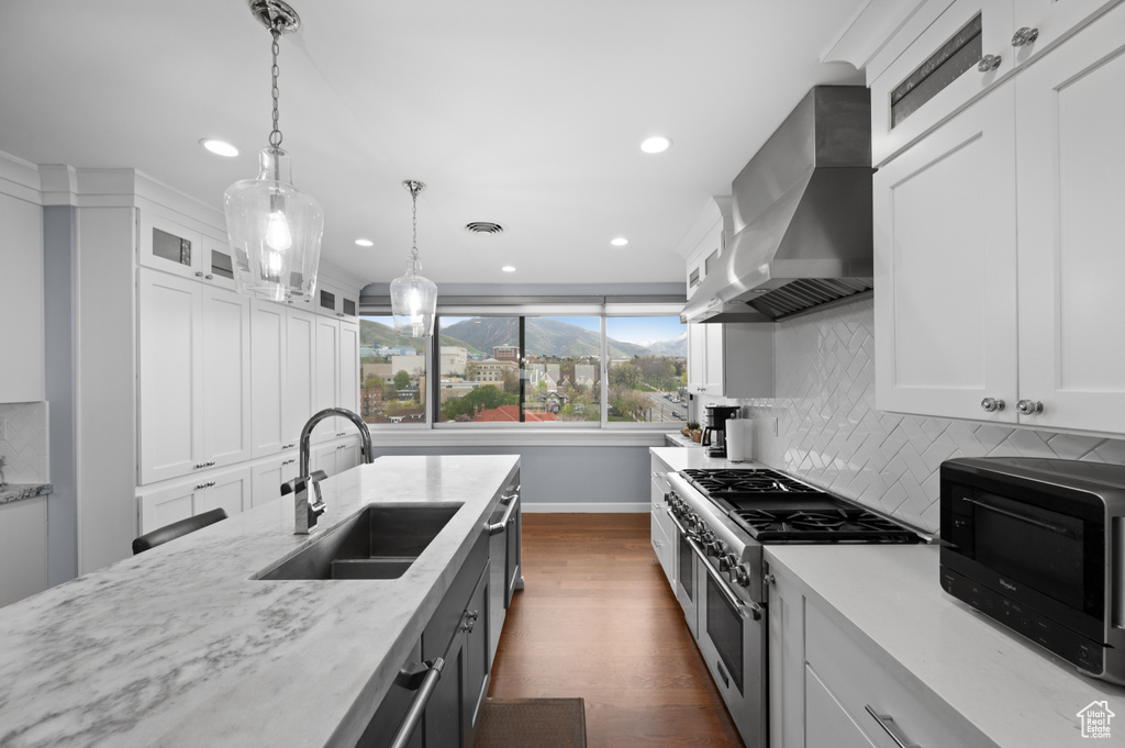 Kitchen featuring wall chimney range hood, recessed lighting, double oven range, and a sink
