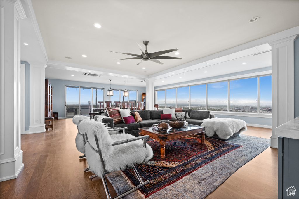 Living room with ceiling fan, decorative columns, wood finished floors, and visible vents