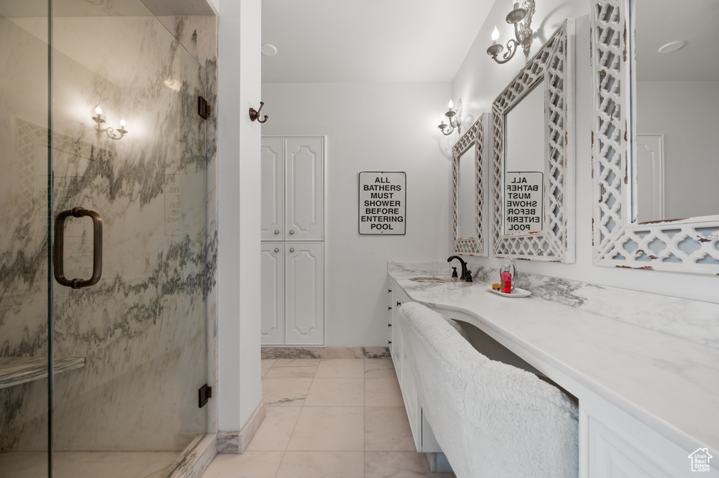 Bathroom featuring vanity, marble finish floor, a marble finish shower, and baseboards