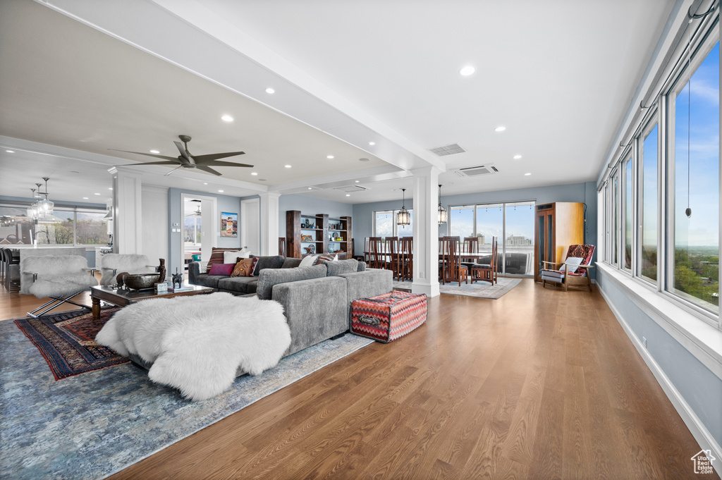 Living room with visible vents, ornate columns, wood finished floors, and a healthy amount of sunlight