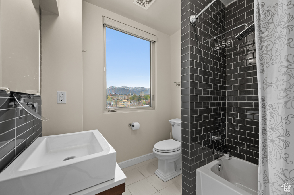 Bathroom featuring visible vents, toilet, baseboards, tile patterned floors, and shower / washtub combination