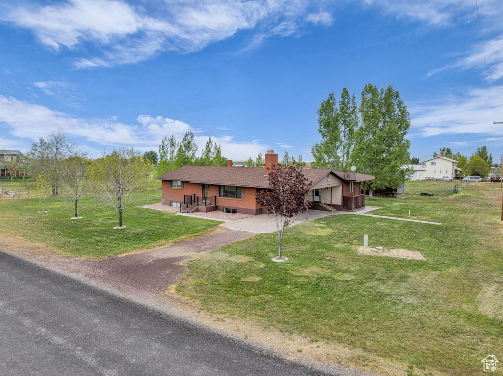 Ranch-style home featuring aphalt driveway, a front yard, and a chimney