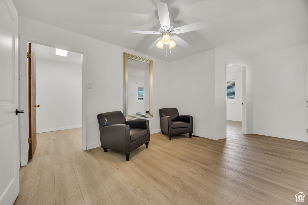 Sitting room featuring baseboards, a ceiling fan, and light wood finished floors