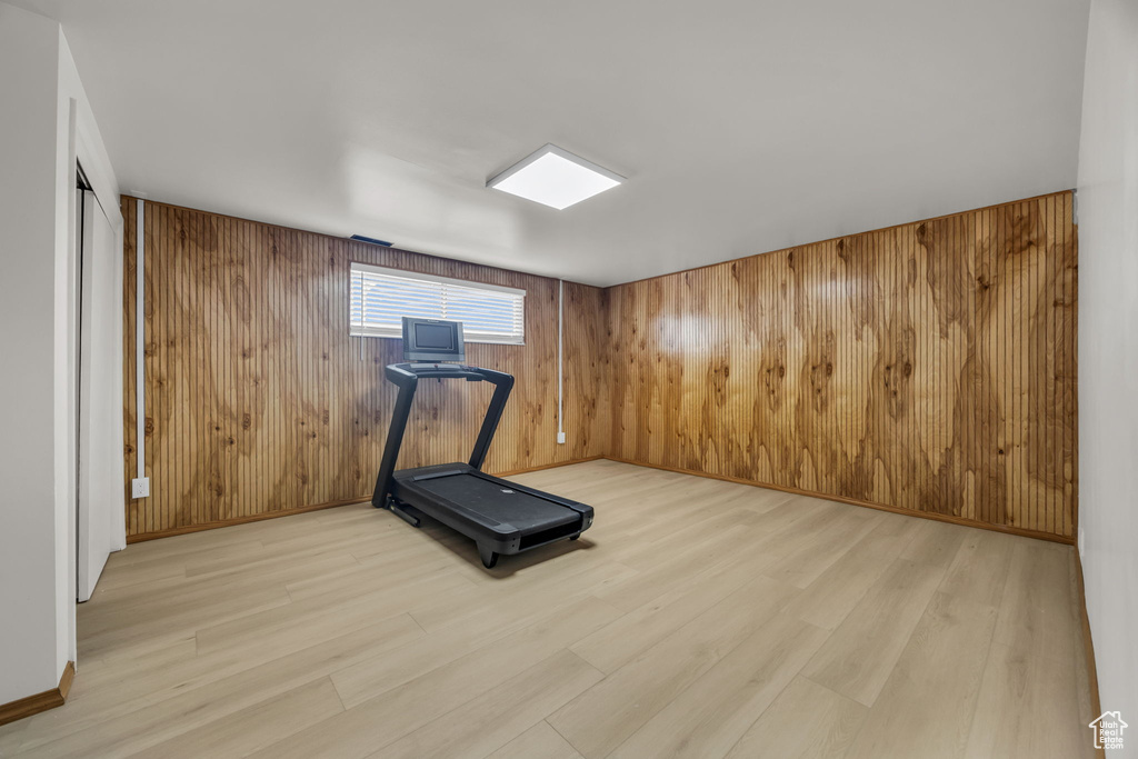 Workout room featuring light wood-style flooring and wooden walls