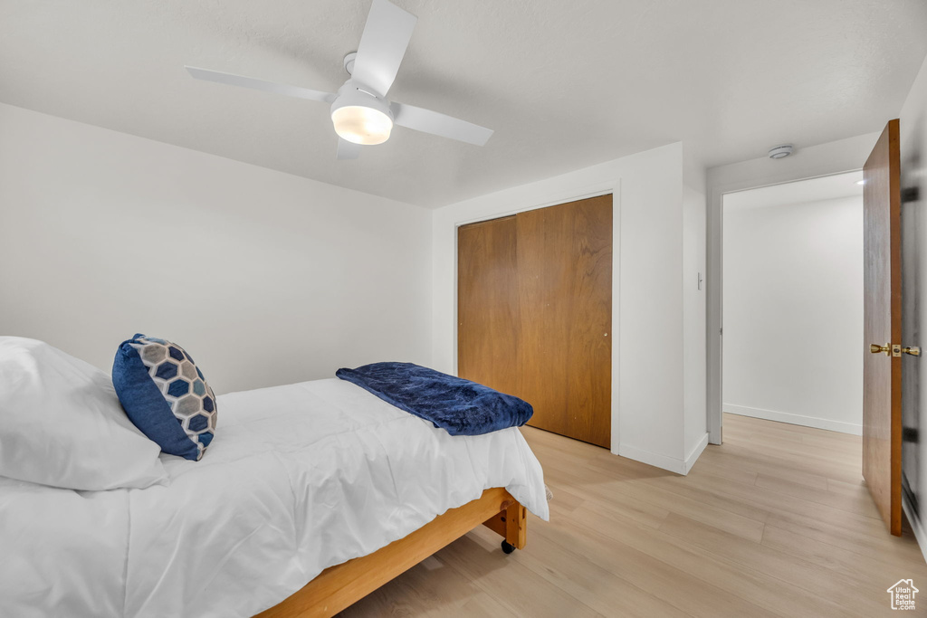 Bedroom featuring baseboards, light wood-style flooring, ceiling fan, and a closet