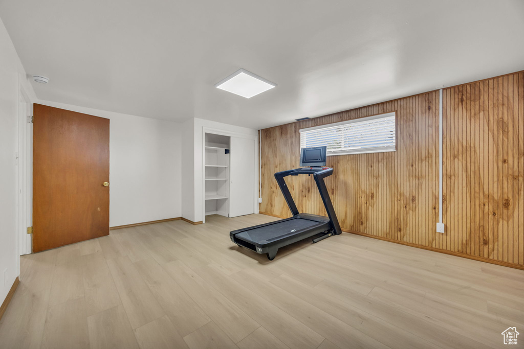Exercise area with built in shelves, baseboards, wood walls, and wood finished floors