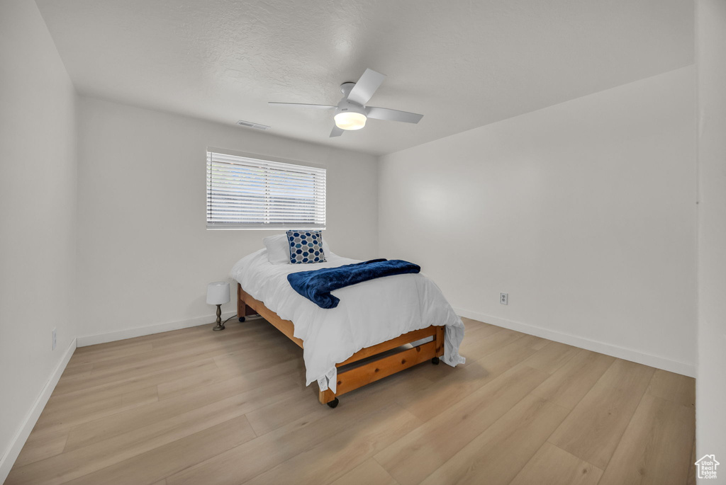 Bedroom featuring a ceiling fan, baseboards, visible vents, and light wood-type flooring