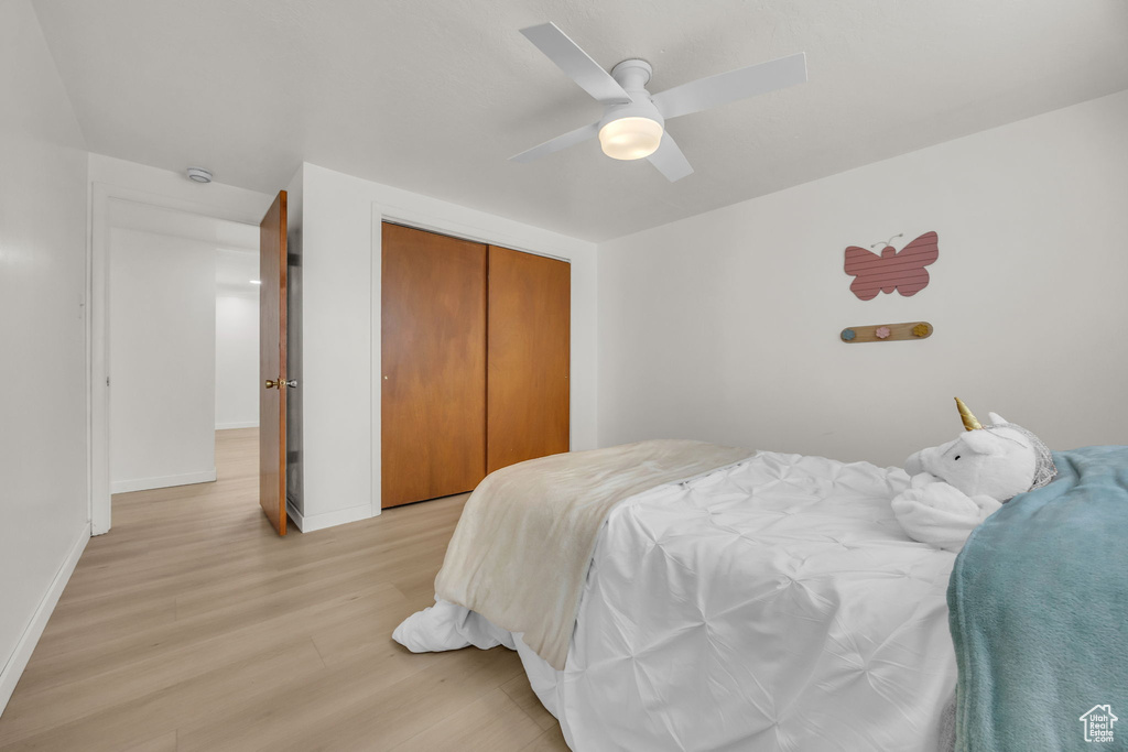Bedroom with baseboards, a ceiling fan, a closet, and light wood-style flooring