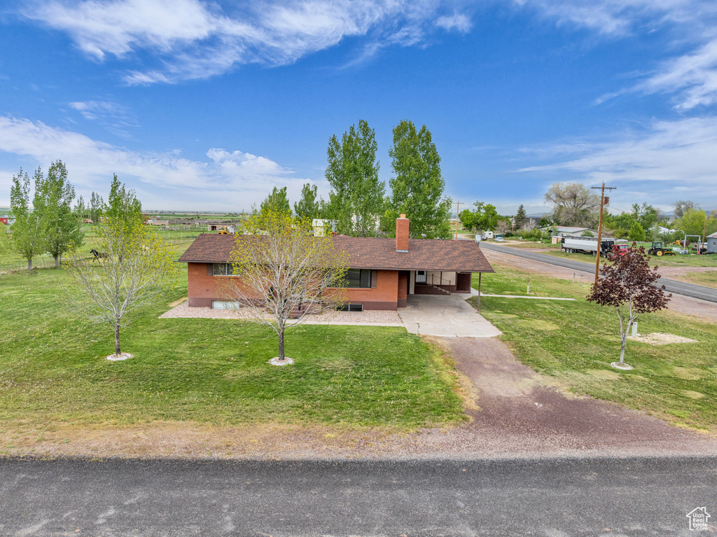 Ranch-style house featuring aphalt driveway, a front yard, a chimney, and a carport