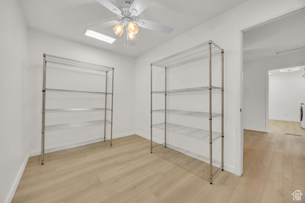 Walk in closet with ceiling fan, washer / dryer, and wood finished floors