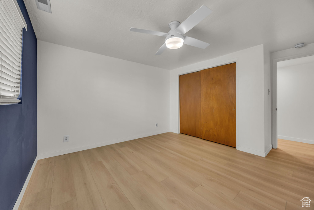 Unfurnished bedroom with baseboards, visible vents, light wood-style flooring, and a closet