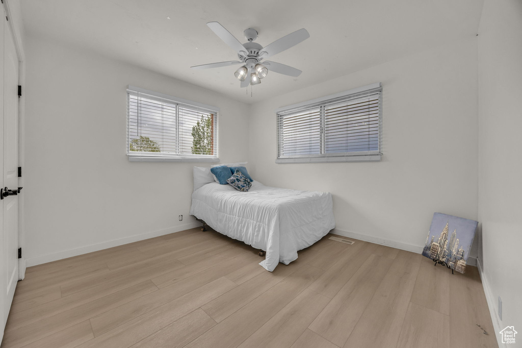 Bedroom with a ceiling fan, baseboards, and light wood-type flooring