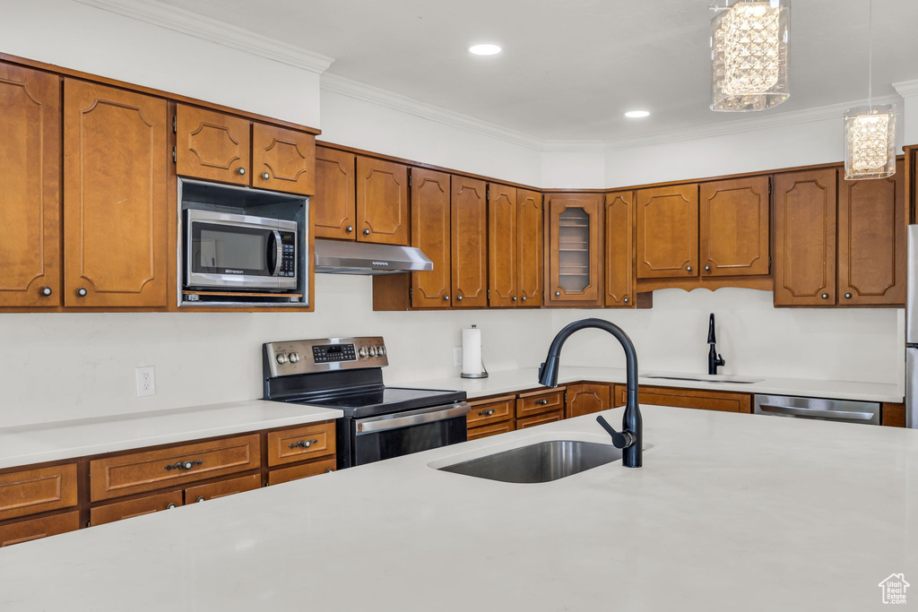 Kitchen featuring a sink, brown cabinetry, stainless steel appliances, and under cabinet range hood