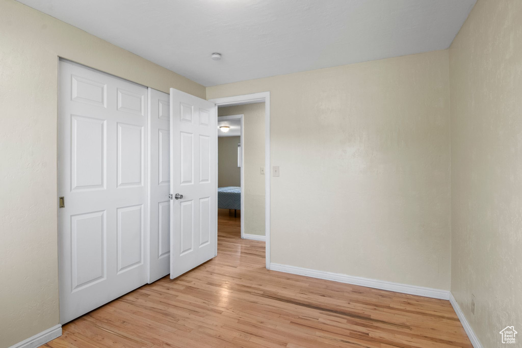Unfurnished bedroom featuring baseboards, light wood finished floors, and a closet