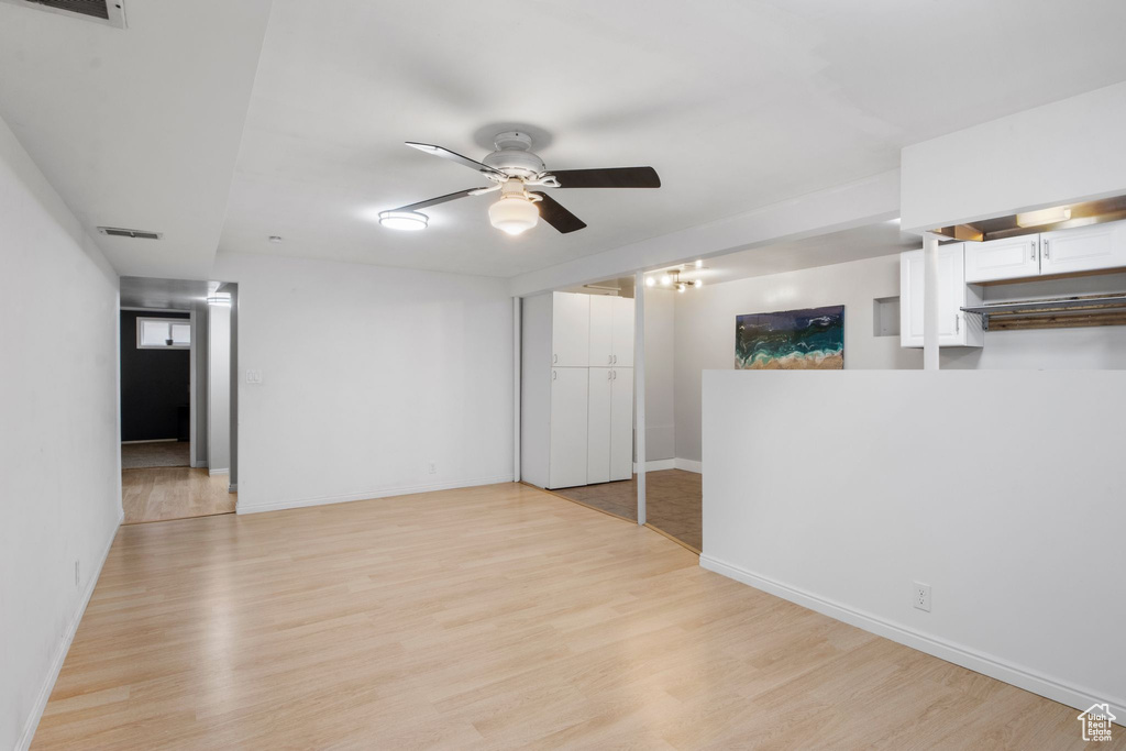 Empty room with ceiling fan, visible vents, baseboards, and light wood finished floors