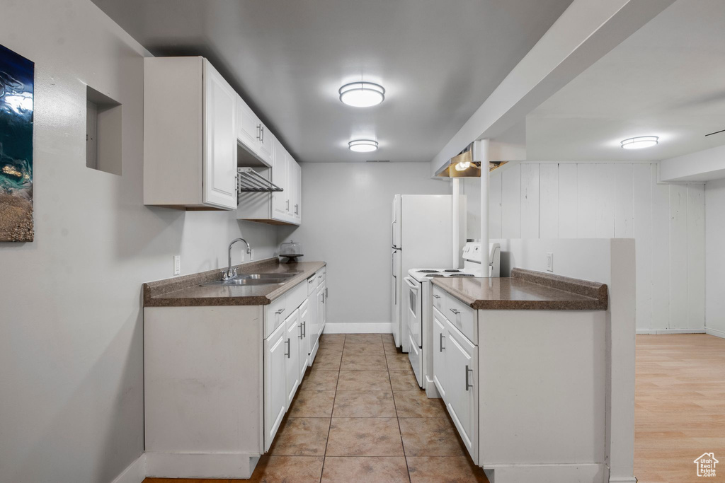 Kitchen featuring electric range, dark countertops, a sink, white cabinetry, and baseboards