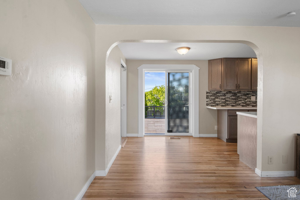 Interior space with baseboards, arched walkways, and light wood finished floors