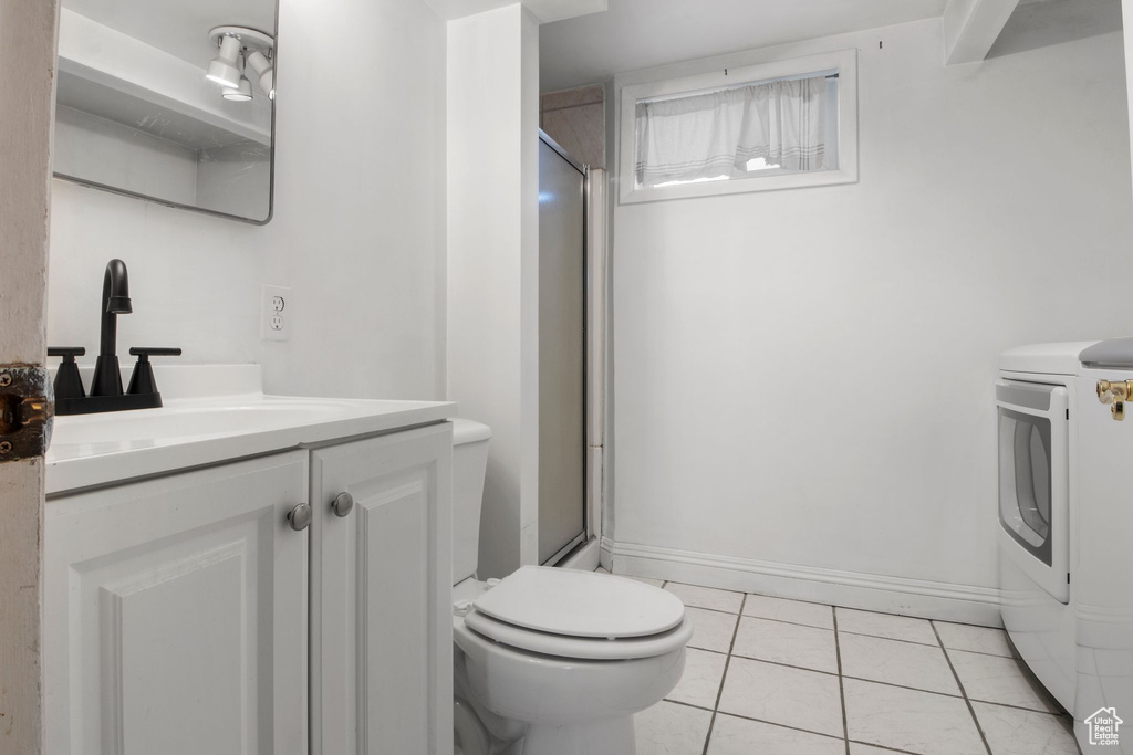 Bathroom with toilet, washer / dryer, a shower stall, and tile patterned flooring