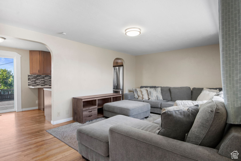 Living room with arched walkways, baseboards, and light wood-style flooring