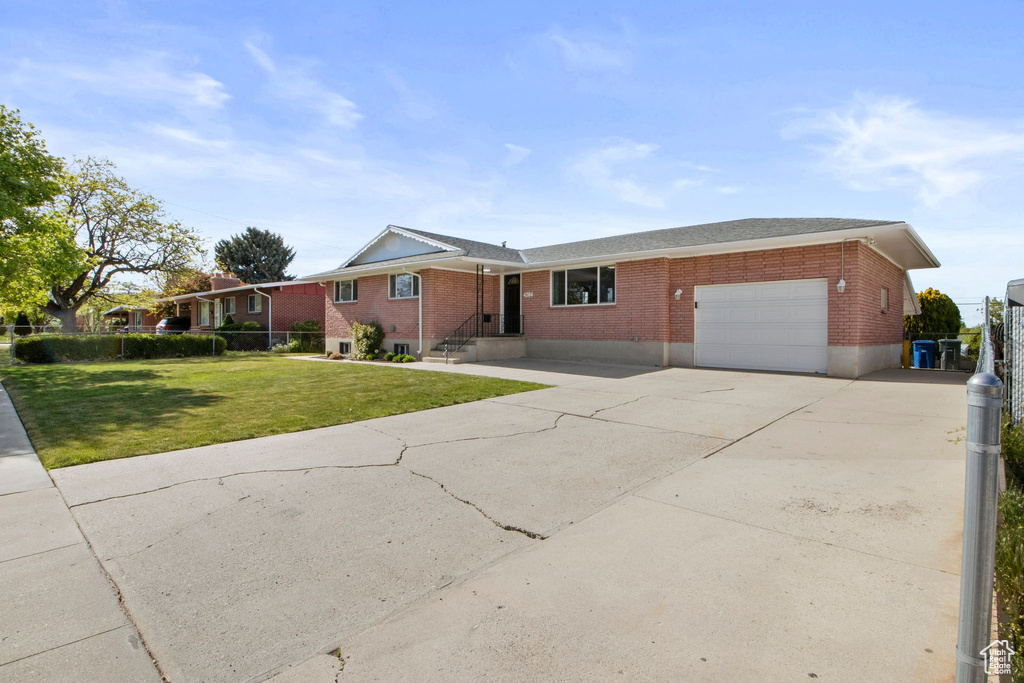 Ranch-style home with concrete driveway, brick siding, a front lawn, and a garage