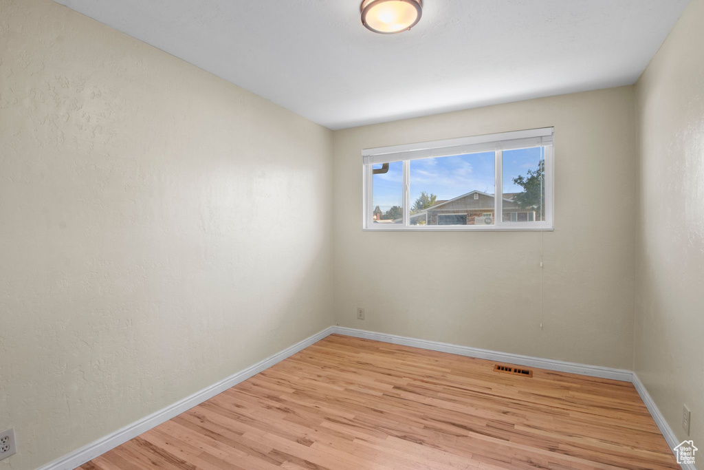 Spare room featuring light wood-style floors, baseboards, and visible vents