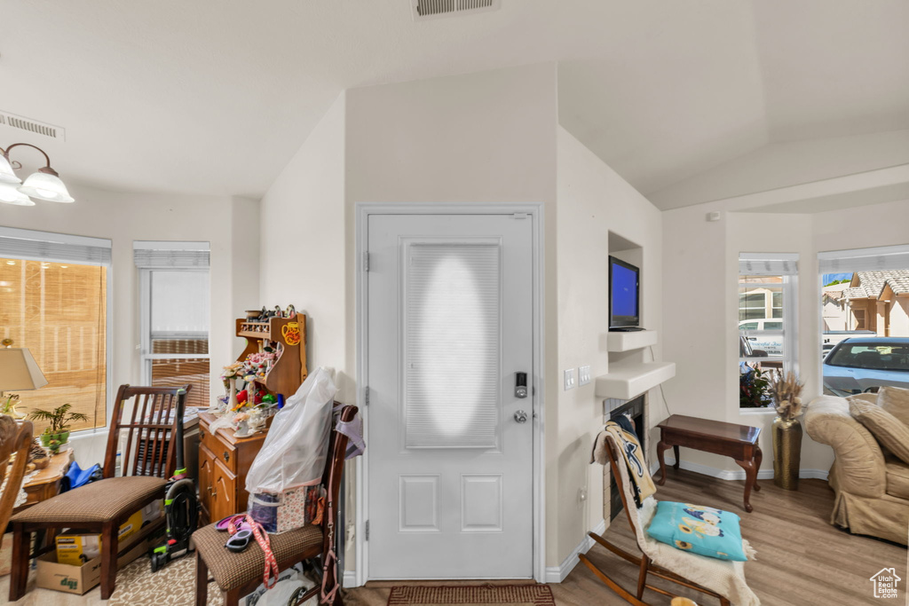 Entryway with visible vents, a fireplace, baseboards, light wood finished floors, and vaulted ceiling