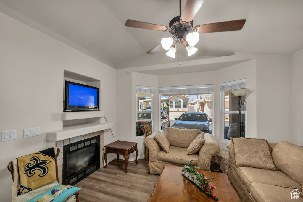 Living area featuring ceiling fan, a fireplace, vaulted ceiling, and wood finished floors