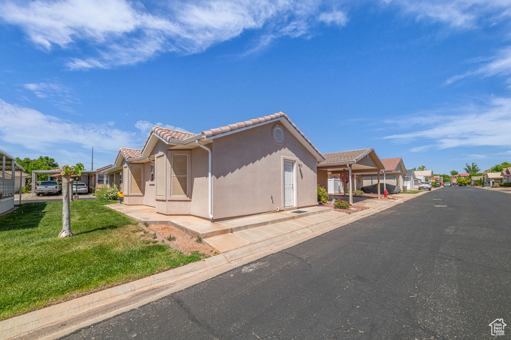 Exterior space with stucco siding, a yard, a tiled roof, and a residential view