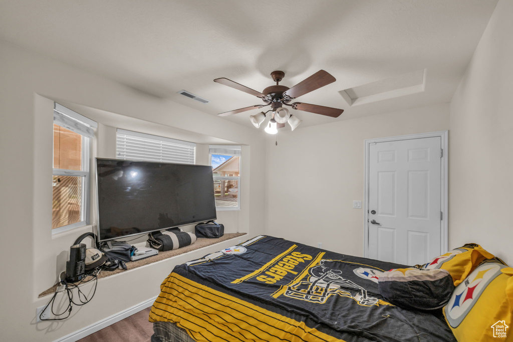 Bedroom with a ceiling fan, visible vents, and wood finished floors