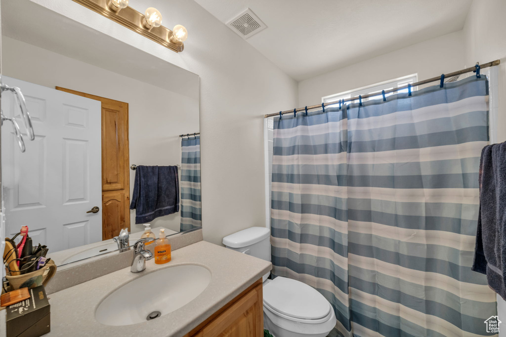 Bathroom featuring vanity, a shower with curtain, toilet, and visible vents