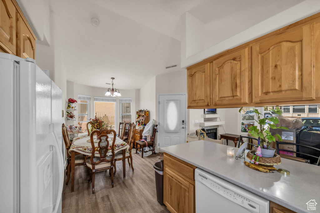 Kitchen featuring visible vents, light countertops, a chandelier, light wood-style floors, and white appliances