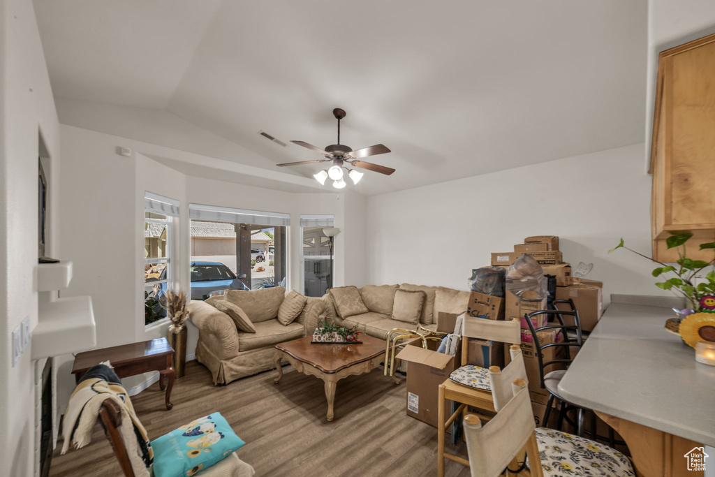 Living room featuring light wood-type flooring, a ceiling fan, lofted ceiling, and visible vents