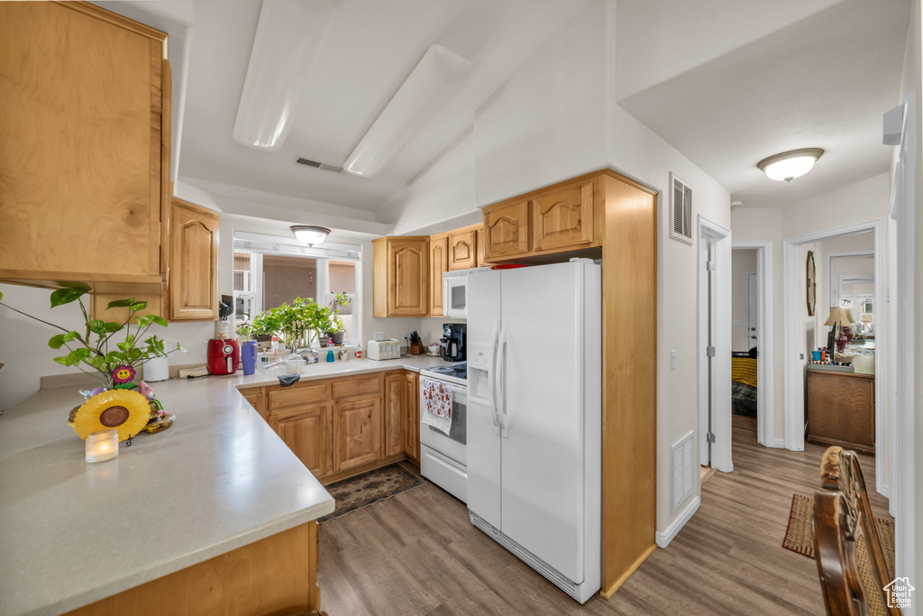 Kitchen featuring light countertops, white appliances, wood finished floors, and visible vents