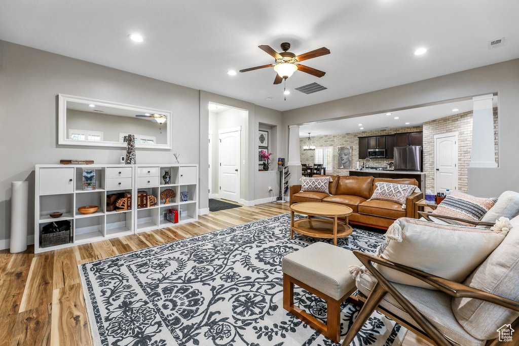 Living room featuring recessed lighting, ceiling fan with notable chandelier, light wood-type flooring, and visible vents