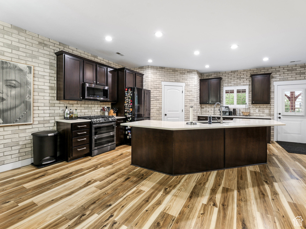 Kitchen featuring light countertops, a sink, light wood-style flooring, and stainless steel appliances