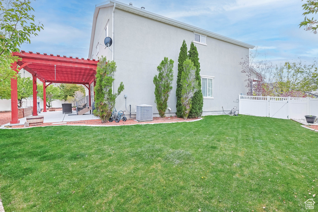 Back of property with a pergola, a patio, a fenced backyard, central AC unit, and a yard