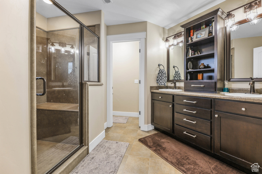 Bathroom with double vanity, a sink, tile patterned flooring, and a stall shower
