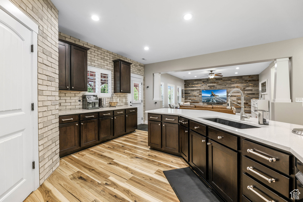 Kitchen with light countertops, a ceiling fan, a sink, and light wood-style floors