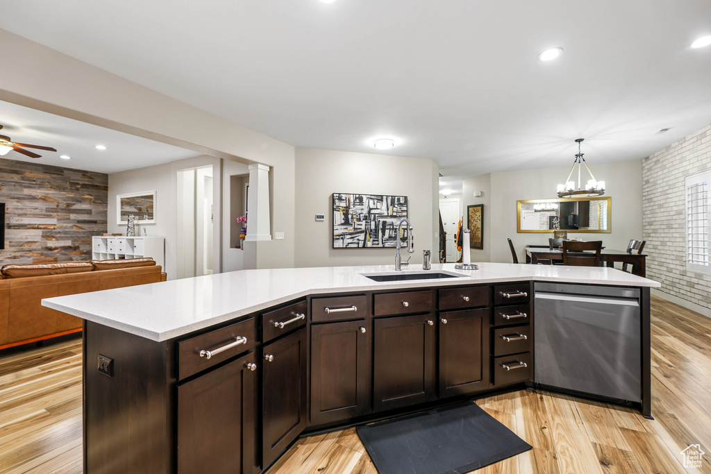 Kitchen with dark brown cabinets, a sink, light countertops, open floor plan, and stainless steel dishwasher