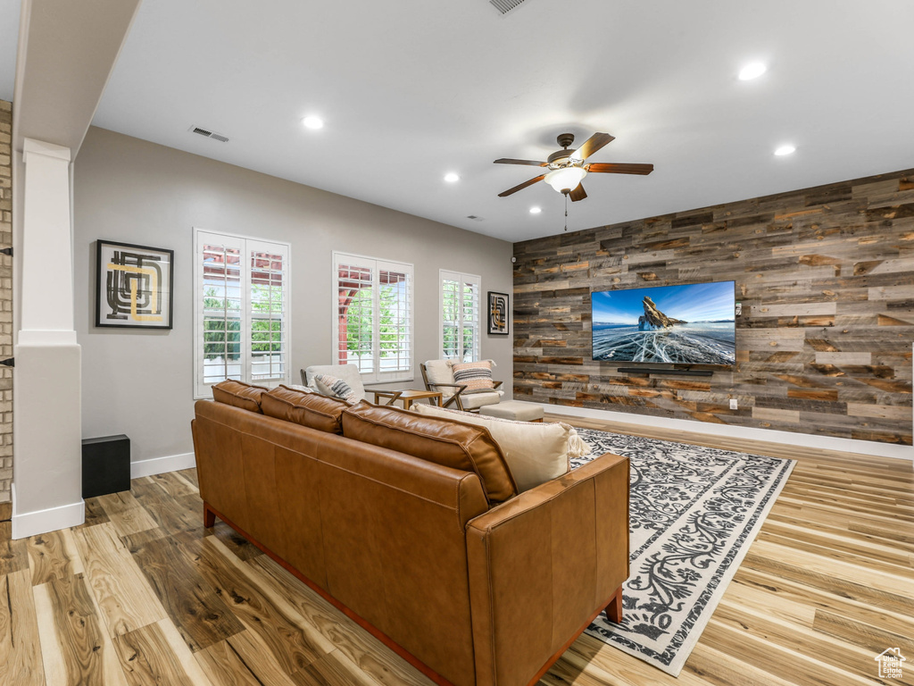 Living area featuring a ceiling fan, wood finished floors, baseboards, an accent wall, and recessed lighting