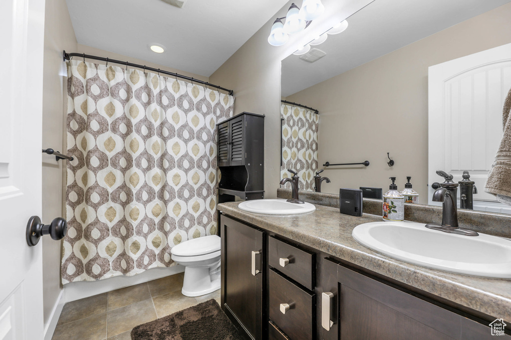 Full bathroom featuring a sink, a shower with curtain, toilet, and double vanity