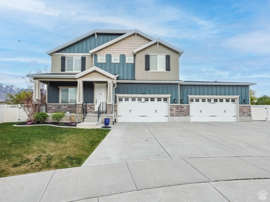 Craftsman house with board and batten siding, a gate, fence, a front lawn, and concrete driveway